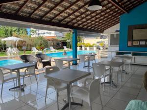 ein Restaurant mit Tischen und Stühlen neben einem Schwimmbad in der Unterkunft Hotel Adventure São Luís in São Luís