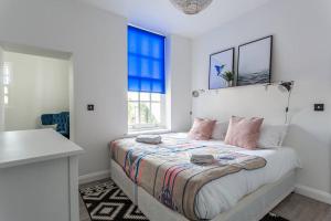 a white bedroom with a bed with pink pillows at Shape of Water in Southend-on-Sea