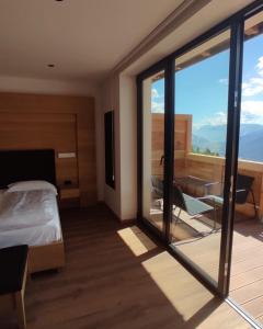 a bedroom with a bed and a desk and a balcony at Hotel Almhof in San Candido