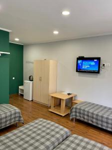 a room with two beds and a tv on the wall at Hotel Crocus in Bosteri