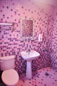 bagno piastrellato rosa con servizi igienici e lavandino di Country Kos Hostel a Kenting