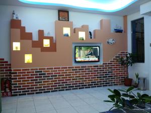a living room with a brick wall with a tv on it at Country Kos Hostel in Kenting
