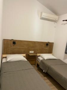 two beds in a small room with a fan at Guest house Kamelija in Budva