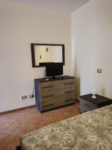 een slaapkamer met een bed en een dressoir met een spiegel bij CASA VACANZE DA NONNA MELA in Alghero