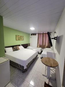 a bedroom with two beds and a table in it at Aton Plaza Hotel in Goiânia