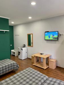 a room with a table and a tv on the wall at Hotel Crocus in Bosteri
