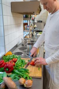 a chef cutting vegetables on a cutting board in a kitchen at NATURION Hotel Hinterzarten in Hinterzarten