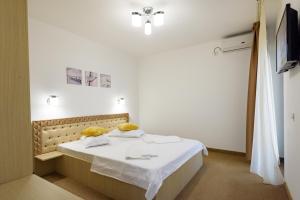a bedroom with a white bed with yellow pillows at SaloS Beach Resort in Mamaia Sat/Năvodari