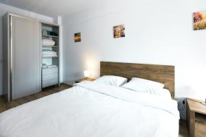 1 dormitorio con 1 cama blanca grande y escritorio en Rivera Apartments - Premium Accomodation en Iaşi