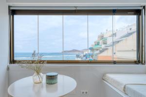 ein Wohnzimmer mit Tisch und großem Fenster in der Unterkunft Stylish Sea View Accommodation Las Canteras in Guanarteme