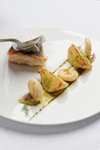 un piatto bianco con un pezzo di cibo con una forchetta di Maison Jenny Hotel Restaurant & Spa a Hagenthal-le-Bas