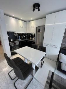 une cuisine avec une table blanche et des chaises noires dans l'établissement Cite Jardin Apart @ 2 Bedroom Apartment, à Sofia