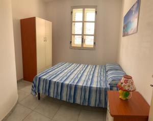 a small bedroom with a bed and a window at Lopadusa trilo 2 in Lampedusa