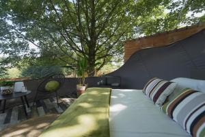 ein Bett auf einer Terrasse mit einem Baum im Hintergrund in der Unterkunft Bulles Odette & Ginette et Tiny House Suzette "Au guet Marais" Etape Insolite in Paliseul