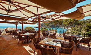 a patio area with tables, chairs and umbrellas at Hotel Aigua Blava in Begur
