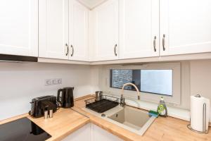 a kitchen with white cabinets and a sink at Modern & Newly built apartment with private garage in Budapest