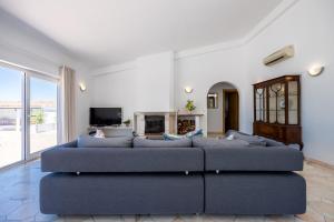 a living room with a blue couch and a fireplace at Villa Mimosa in Santa Bárbara de Nexe