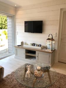 a living room with a table with a tv on the wall at Étoile des Monje in Cucq