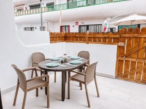 a dining room table with chairs and an umbrella at Dahlia Apartment DunaSol in Corralejo
