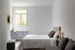 Habitación blanca con cama y escritorio en Ronda9 central suites, en Madrid