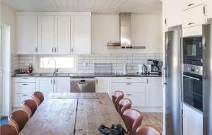 Una cocina con una mesa de madera y gabinetes blancos. en Cozy Apartment In Sysslebäck With Wifi, en Sysslebäck