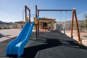a playground with a blue slide and swings at Casas Rurales de Vicorto in Elche de la Sierra