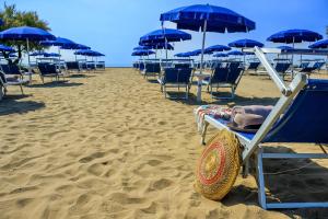 a row of chairs and umbrellas on a beach at Pareus Beach Resort in Caorle