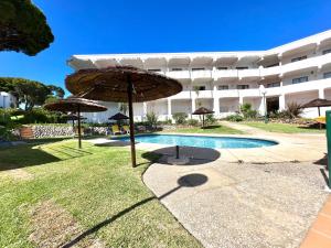 a pool with umbrellas in front of a building at Sea Gardens - Alvaflor - Vilamoura in Vilamoura