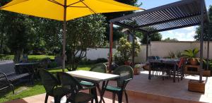eine Terrasse mit einem Tisch und Stühlen sowie einem gelben Regenschirm in der Unterkunft Chambre d'Hôtes le Gachignard in Courlay