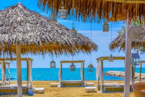 a beach with chairs and a straw umbrella and the ocean at Pareus Beach Resort in Caorle