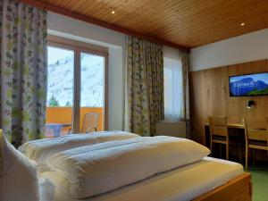 sypialnia z 2 łóżkami, stołem i telewizorem w obiekcie Pension Edelweiss w mieście Damüls