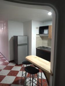uma cozinha com uma mesa, 2 bancos e um frigorífico em ESTADIO APARTA HOTEL 201 em Medellín