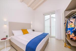 a white bedroom with a bed and a window at Pareus Beach Resort in Caorle