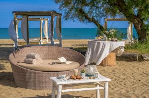 a rattan chair on the beach with a table and a tableablish at Pareus Beach Resort in Caorle