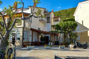 Ein Haus mit einem Berg im Hintergrund in der Unterkunft Apartmani Kordić in Rab