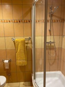 een badkamer met een douche en een gele handdoek bij Bellis Apartment in Szczecin