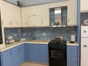 cocina con armarios azules, fregadero y fogones en Stavri's Apartment, en Sarandë