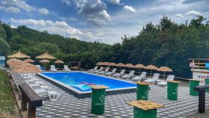 una gran piscina con sillas y sombrillas en Etno Village Dolina Sreće, en Vitez