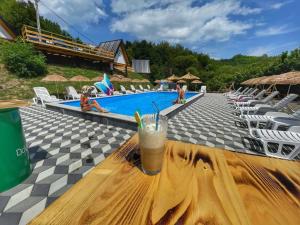 a drink on a wooden table next to a swimming pool at Etno Village Dolina Sreće in Vitez