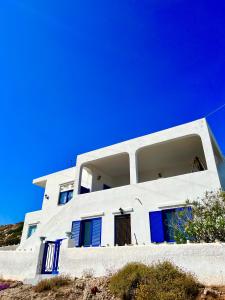 una casa blanca con puertas azules en una colina en Comfortable house with seaview in Donousa en Donoussa