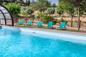 una piscina con sedie a sdraio blu accanto a una piscina di Hotel Vilar Rural d'Arnes by Serhs Hotels a Arnés