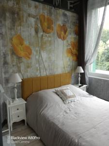 1 dormitorio con 1 cama con flores amarillas en la pared en Studio Malou, cuisine, salle d'eau, terrasse amenagée, en Olliergues