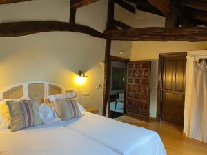 El Jardin de las Magnolias Hotel في Quintana de Soba: غرفة نوم بسرير ابيض كبير بسقوف خشبية