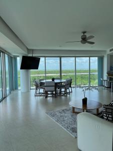 uma sala de estar com uma mesa e cadeiras e uma ventoinha de tecto em Fabuloso departamento de lujo frente al mar em Cancún