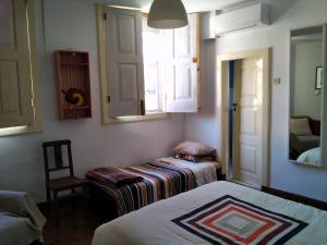 a bedroom with two beds and a window and a chair at Casa da Vinha Grande in Poiares