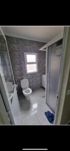 La salle de bains est pourvue de toilettes, d'un lavabo et d'une douche. dans l'établissement Comforts apartments 1, à Fnideq