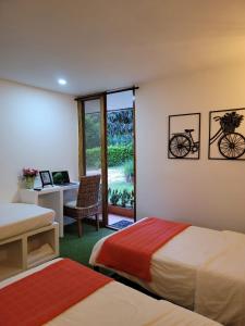 a bedroom with two beds and a desk with a bike on the wall at Casa Ensueño Hogar Boutique in Guaduas
