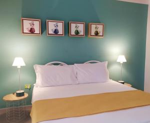 a bedroom with a bed with four pictures on the wall at Hotel Galman in Carloforte