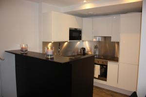 a kitchen with white cabinets and a black counter top at Appartement Saint Thomas Prestige in Strasbourg