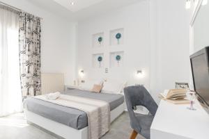 a white bedroom with a bed and a desk at Naxos Apartment in Naxos Chora